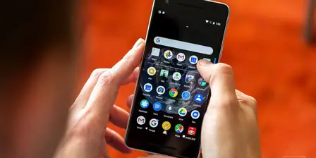 Hand holding an Android phone showing the app drawer